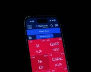 Smartphone screen showing a stock market app (StockRadars) with red tiles for IVL, KBANK, EA, and ADVANC; values like 24.30, 153.50, 8.50, 263.00 visible