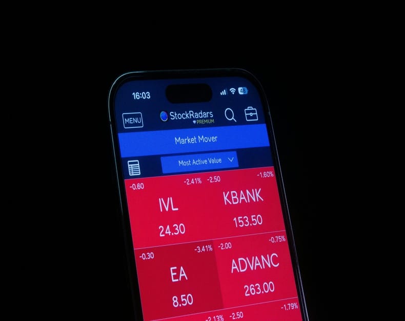 Smartphone screen showing a stock market app (StockRadars) with red tiles for IVL, KBANK, EA, and ADVANC; values like 24.30, 153.50, 8.50, 263.00 visible