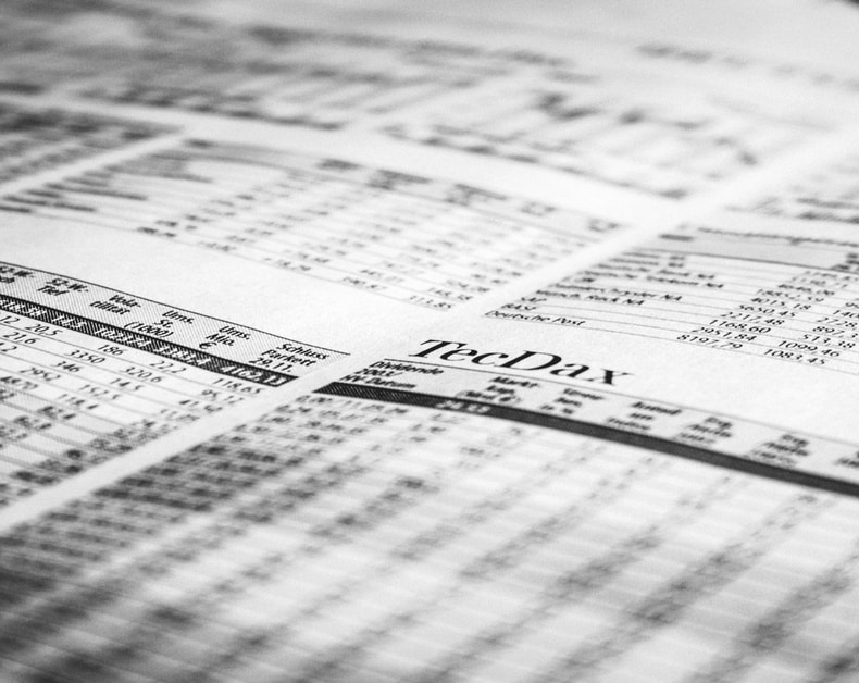 Close-up of a black-and-white newspaper page with stock tables and the word 'TechDay' visible, conveying financial news.