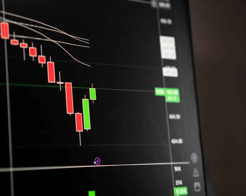 Stock chart with red and green candlesticks on a dark screen showing price movement and trend lines.