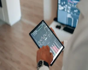 Person holding a tablet displaying a stock chart and market data in a trading app